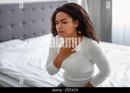 Junge schwarze Frau hustet, leidet an Halsschmerzen Stockfoto