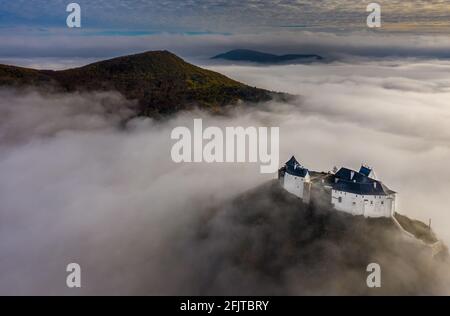 Fuzer, Ungarn - Luftpanorama auf das schöne Schloss von Fuzer, das an einem nebligen Herbstmorgen mit Zemplen-Bergen und aus dem Nebel ragt Stockfoto