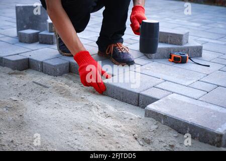 Der Meister in gelben Handschuhen legt Pflastersteine Stockfoto