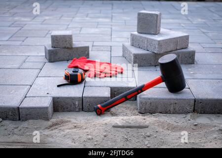 Der Meister in gelben Handschuhen legt Pflastersteine Stockfoto