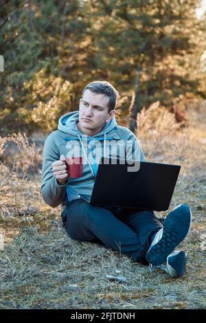 Selbstisolierung, Ablenkungen zu Hause Konzept. Nach der Arbeit die Steckdose ziehen, zu viel funktioniert. Männer draußen auf der Natur mit Notebook arbeitet. Abends Stockfoto