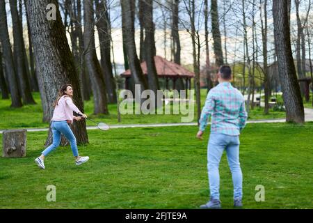 Junges glückliches Paar, das im Park Badminton spielt Stockfoto