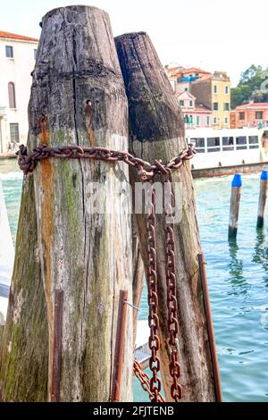 Alte hölzerne Ankerplatz Säulen für Boote . Platz zum Parken von Gondeln in Venedig. Rostige Ketten für festgetäute Boote Stockfoto