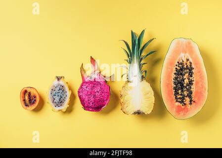 Kreatives Layout aus exotischen Früchten - Papaya, Ananas, Drachenfrucht, Pitahaya, Tamarillo-Frucht auf gelbem Hintergrund. Flach liegend. Draufsicht. Kopieren Stockfoto