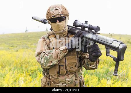 Der Soldat der Spezialeinheiten geht mit einem Scharfschütze über das gelbe Feld Nahaufnahme des Gewehr Stockfoto