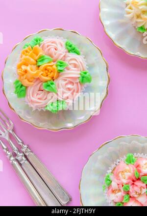 Vertikale über Kopf Bild von hübschen Tasse Kuchen zart vereizt Mit russischen Icing Tips rosa Hintergrund mit Copy Space Stockfoto