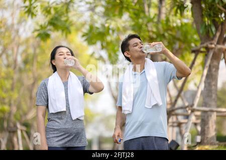 Senioren, alten Mann und Frau sprechen und trinken Wasser nach dem Training im park Stockfoto