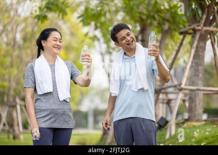 Senioren, alten Mann und Frau sprechen und trinken Wasser nach dem Training im park Stockfoto