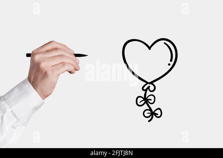 Mann mit einem Stift mit handgezeichneter Herzform fliegenden Ballon-Symbol. Stockfoto