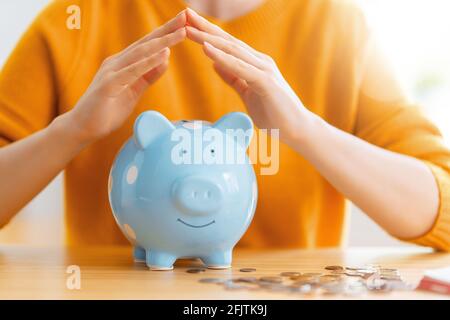 Frau sitzt am Schreibtisch mit Sparschwein. Konzept der Verwaltung des Familienbudgets. Stockfoto