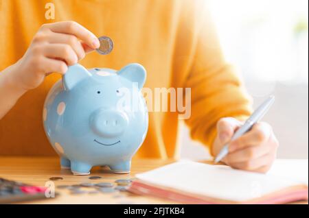 Frau sitzt am Schreibtisch mit Sparschwein. Konzept der Verwaltung des Familienbudgets. Stockfoto