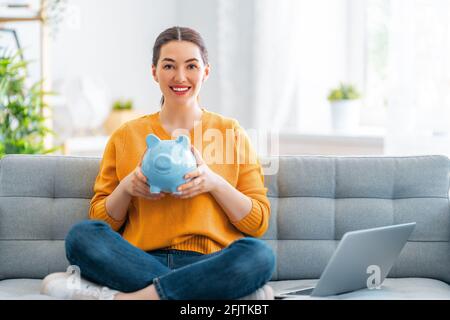 Frau sitzt auf dem Sofa mit Sparschwein. Konzept der Verwaltung des Familienbudgets. Stockfoto