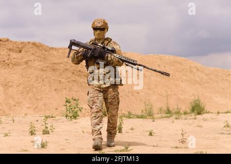 Bewaffneter Spezialeinsatzsoldat mit Gewehr in der Wüste während der Militäroperation. Konzept der militärischen Anti-Terror-Operationen, Sondereinsätze der NATO-Truppen. Stockfoto