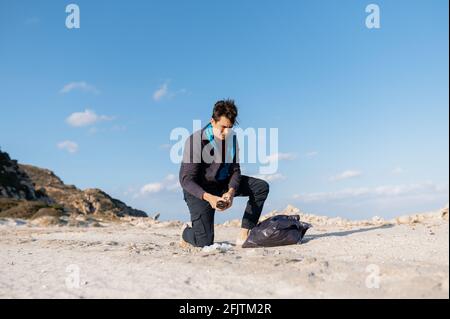 Junger Freiwilliger, der sich an Abfall vom Strand erinnerte und in eine Tasche legte. Umweltschutz. Stockfoto