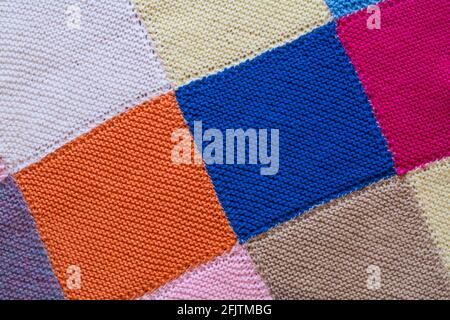 Zusammengenähte gestrickte Quadrate zu einer Decke, Nahaufnahme von Quadraten in gestrickter Decke Stockfoto