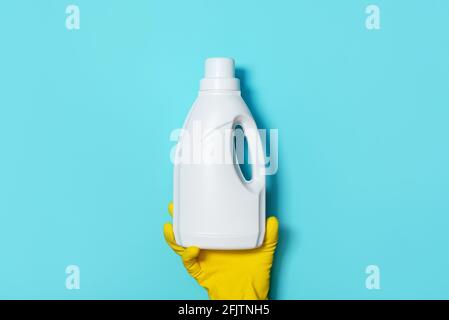 Hand in Handschuh mit weißer Plastikflasche mit Reinigungsprodukt, Haushaltschemikalien. Speicherplatz kopieren. Reinigungskonzept. Chemische Reinigung im Haushalt Stockfoto