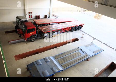 Eine Gruppe von Mechanikern arbeitet an 2 Lkw, die in einer Reparaturwerkstatt für schwere Lkw geparkt sind. Stockfoto