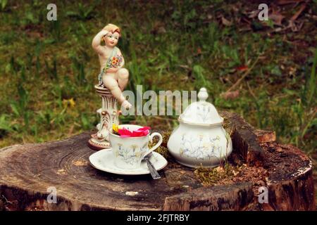 Schöne antike Keramik mit handbemalten Lamm mit Tasse und Zuckerdose mit Frühlingsblumen auf Holzstumpf und verschwommen Bukolischer Hintergrund Stockfoto