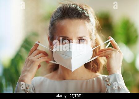 Covid-19-Pandemie. Porträt einer eleganten Frau in grauer Bluse mit ffp2 Maske. Stockfoto