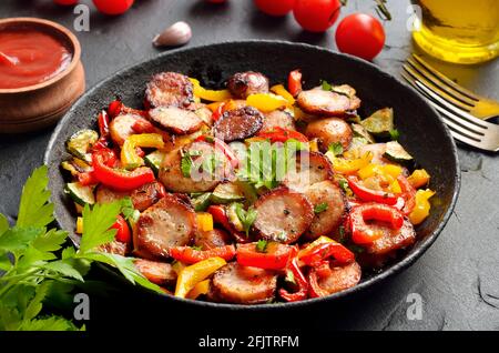 Scheiben gebratener Würstchen mit Gemüse und Gewürzen in Bratpfanne, Nahansicht Stockfoto