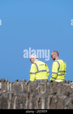 Zwei Cormac-Arbeiter tragen fluureszend gelbe Hi-viz-Sicherheitsjacken, die vor einem strahlend blauen Himmel gesehen werden. Stockfoto