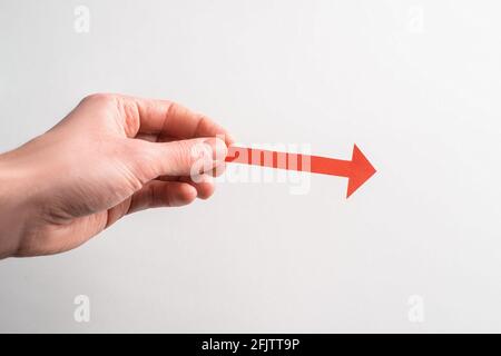 Hand mit einem roten Papierpfeil, der nach rechts zeigt Stockfoto