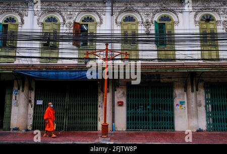 Ein thailändischer Mönch geht an einem bunten alten Gebäude in Bangkok, Thailand, vorbei Stockfoto