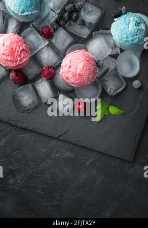 Kirsch- und Brombeereis auf Eiswürfeln auf schwarzem Hintergrund. Vertikale Ansicht. Sommerdesserts. Stockfoto