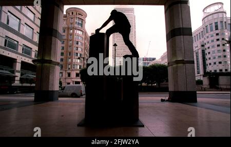 Ein nicht identifizierter Mann klettert auf eine nicht identifizierte Skulptur vom 1999. August in den Docklands. Mehrere Sculpures werden in und um Canary Wharf installiert Stockfoto