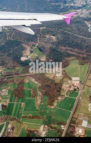 Blick vom Flugzeugfenster auf grüne Felder und Wälder Auf dem Hintergrund des Flügels Stockfoto