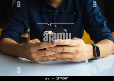 Männer Hand hält SMS mit mobilen entspannen zu Hause. Mockup Bild leeren Textfeld Rahmen für Nachricht. Soft-Fokus und über Licht im Hintergrund Stockfoto