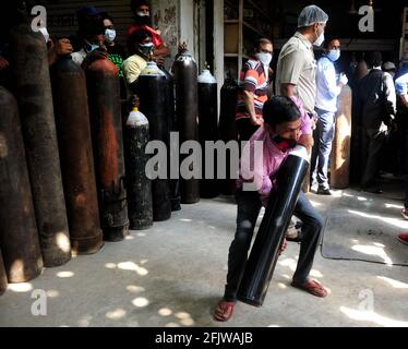 Neu-Delhi, Indien. April 2021. Ein Mann hebt eine nachgefüllte medizinische Sauerstoffflasche für COVID-19-Patienten vor einem Geschäft in Neu-Delhi, Indien, am 26. April 2021. Quelle: Partha Sarkar/Xinhua/Alamy Live News Stockfoto