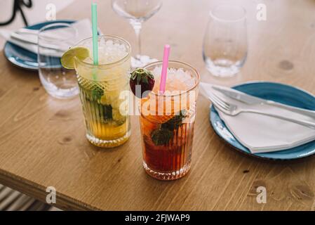 Zwei Mojito-Cocktails mit gereiftem Rum, Minze und verschiedenen Früchten. Eine Erdbeere und die andere Passionsfrucht Stockfoto