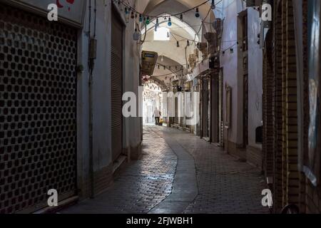 Mann am Ende einer Innengasse mit geschlossenen Rollläden im Großen Basar von Kashan, Iran. Stockfoto