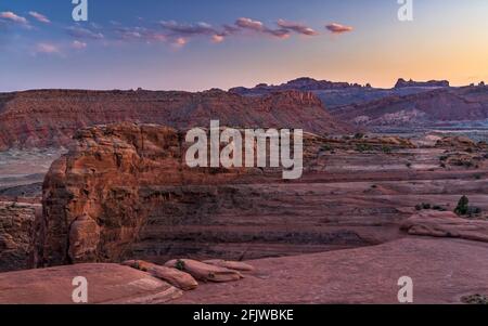 Blick über das Cache Valley in Richtung der Fensterabteilung von der Delicate Arch Bowl in der Abenddämmerung im Arches National Park in der Nähe von Moab, Utah. Stockfoto