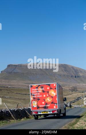 Tesco-Lieferwagen, der eine Landstraße in den Yorkshire Dales entlang fährt, wobei Penyghent im Hintergrund fiel. Yorkshire Dales National Park, Großbritannien. Stockfoto