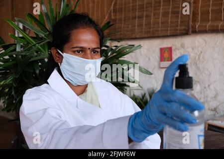 Junge Inderin mit Ärzteinuniform, Handschuhen und Desinfektionsmittel Stockfoto