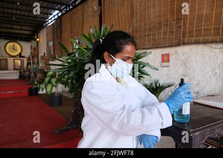 Junge Inderin mit Ärzteinuniform, Handschuhen und Desinfektionsmittel Stockfoto
