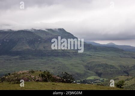 Ein Sturm, der sich in den Drakensberg-Bergen Südafrikas sammelt und die tief liegenden Wolken die Gipfel der fernen Berge verdunkeln Stockfoto