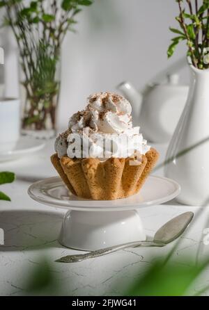 Kuchen mit einem Korb aus Mürbeteig und Proteincreme Auf einem weißen Teller mit einem harten Licht Stockfoto