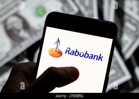 In dieser Abbildung ist das Logo des niederländischen multinationalen Banken- und Finanzdienstleisters Rabobank zu sehen, das auf einem Smartphone mit US-Dollar (USD) im Hintergrund angezeigt wird. Stockfoto