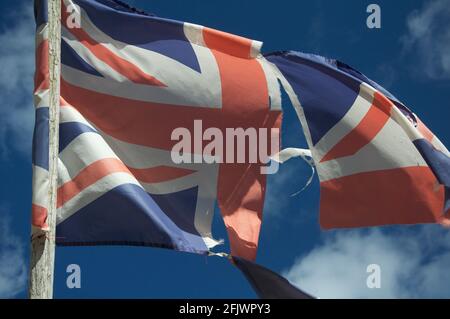 Alt und verblasst. Die Unionsflagge des Vereinigten Königreichs zerflattert und zerrissen, flattert und flattert im Wind gegen den Himmel. England, Großbritannien, Großbritannien. Stockfoto