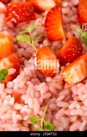 Risotto mit Erdbeerfrüchten in einem Gericht serviert. Nahaufnahme flach liegend mit Kopierplatz. Italienische Gourmetküche. Selektiver Fokus. Stockfoto