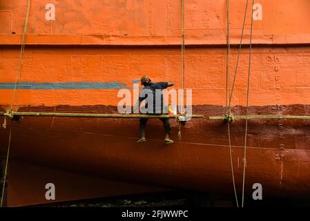 Ein Hafenarbeiter färbt ein Frachtschiff an der größten Hafenkreuzung im Flusshafen von Dhaka, Bangladesch. Stockfoto