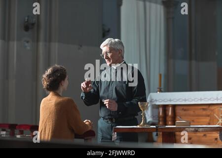Der Oberpriester segnete die treue Frau in der Kirche Stockfoto