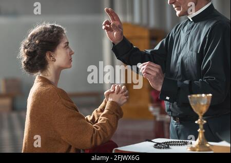 Älterer Mann segnet die Frau, während sie im betet kirche Stockfoto