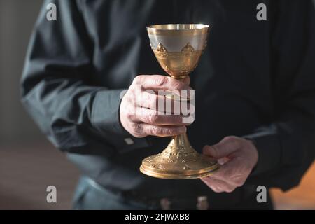 Nahaufnahme eines hochrangigen Priesters, der den Kelch in der Kirche hält Stockfoto