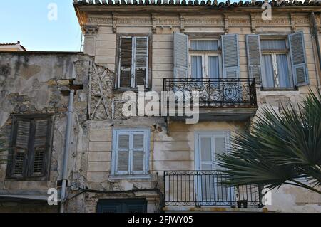 Altes Haus im neoklassizistischen Stil mit verwitterter Wand, handgefertigtem Eisengeländer und hölzernen Fensterläden in Nafplio, Argolis Peloponnes, Griechenland. Stockfoto