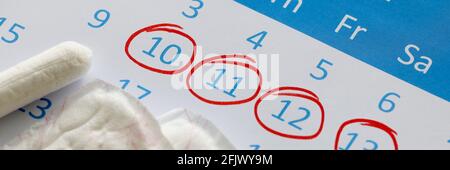 Sanitär-Pads und Tampons stehen auf dem Kalender. Die Zahlen sind in einem roten Stift eingekreist Stockfoto