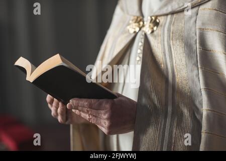 Nahaufnahme eines Priesters, der während der Zeremonie die Bibel hält und Gebete liest In der Kirche Stockfoto